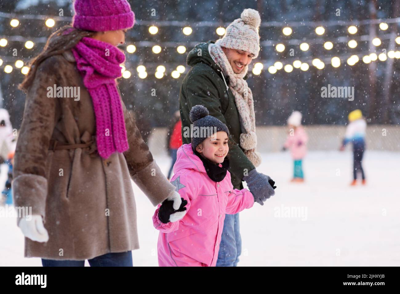 happy family alla pista di pattinaggio all'aperto in inverno Foto Stock