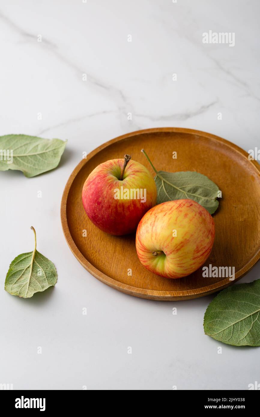 Due mele biologiche fresche piatto di legno su superficie leggera raccolto concetto cibo copia spazio frutti Foto Stock