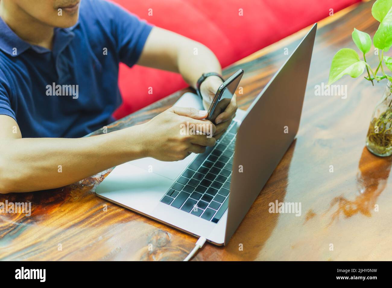 Freelance che naviga sullo smartphone mentre lavora su un notebook a casa. Foto Stock