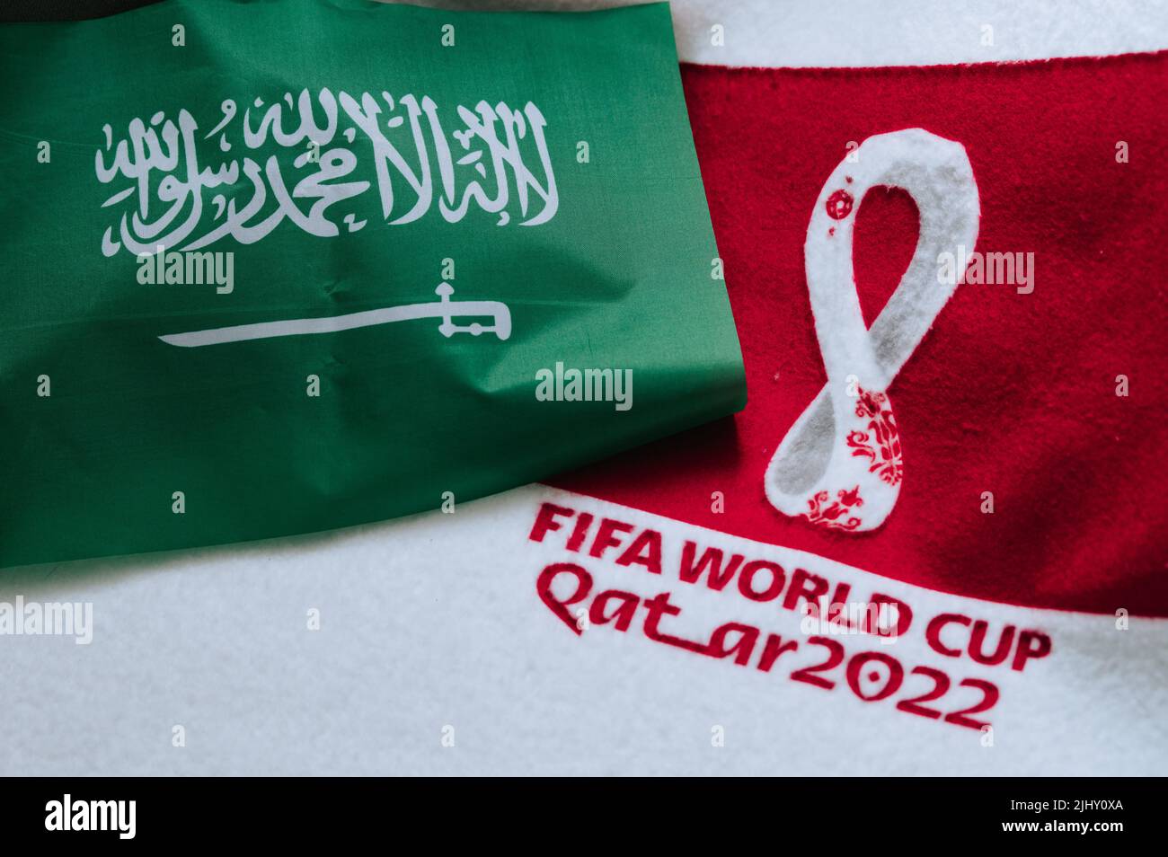 QATAR, DOHA, 18 LUGLIO 2022: Bandiera nazionale dell'Arabia Saudita e logo della Coppa del mondo FIFA in Qatar 2022 su tappeto rosso. Sfondo dello sport di calcio, spazio di modifica. QA Foto Stock