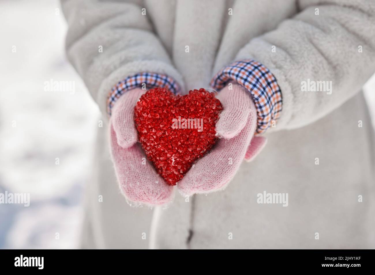 primo piano della bambina che tiene il cuore in inverno Foto Stock