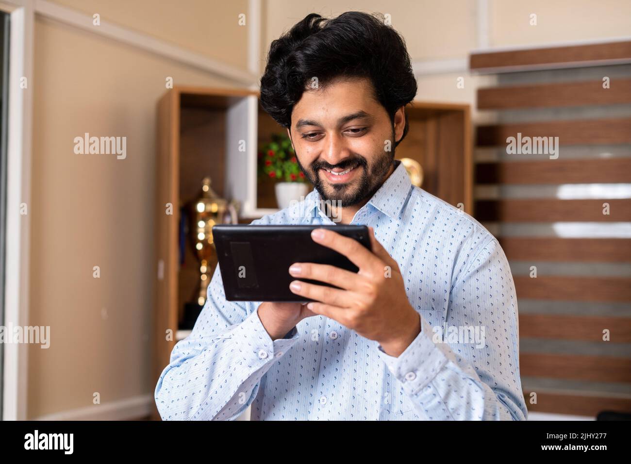 Buon sorridente dipendente aziendale che utilizza il tablet digitale in ufficio: Concetto di approvazione del progetto, successo dell'affare aziendale e promozione del lavoro. Foto Stock