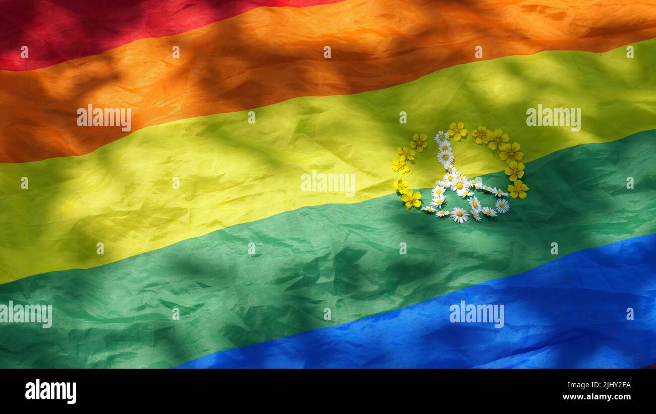 Simbolo di pace con fiori su sfondo arcobaleno LGBT bandiera in orgoglio mese di dignità e diversità. Primo piano, copia spazio, incolla testo, giorno estivo soleggiato. Foto Stock