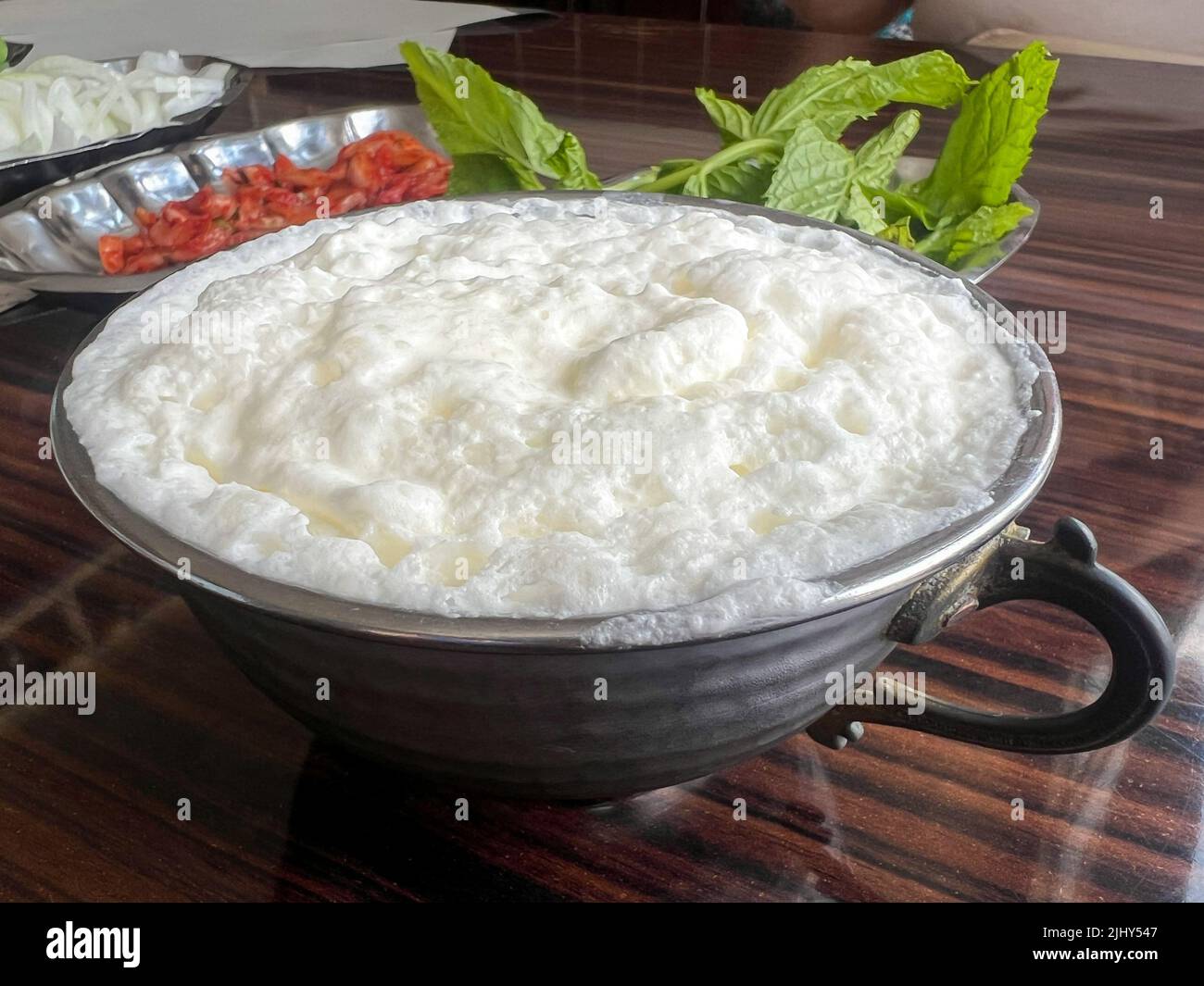 Latticello, bevanda tradizionale yogurt o bevanda conosciuta come ayran in turco con schiuma in argento in metallo tazza sul tavolo in Turchia. Latticello, tradizionale Foto Stock