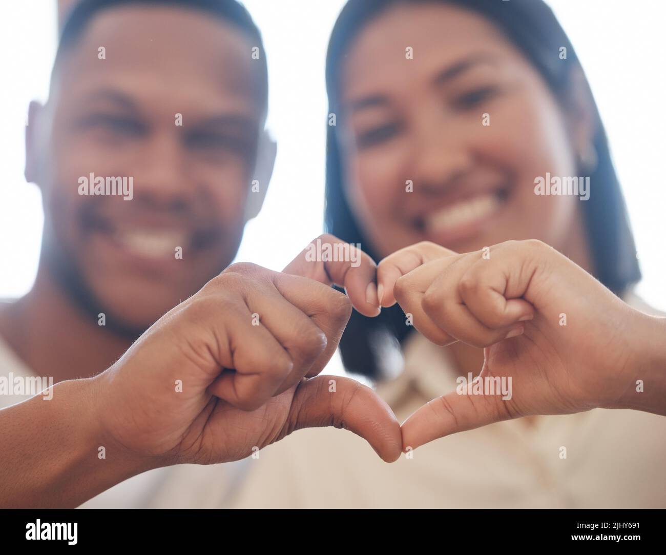 Primo piano di coppia mista gara che fa il cuore forma con le mani. Due amanti che mostrano segno di cuore unendo le dita. Forma d'amore Foto Stock