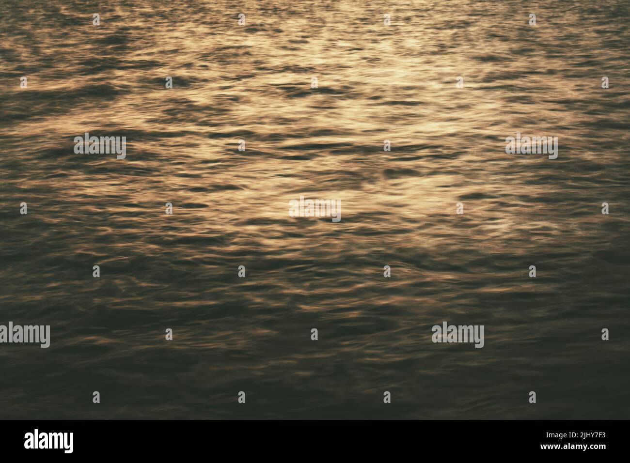 Sfocato sfondo ondulato della superficie del mare al tramonto. Foto Stock