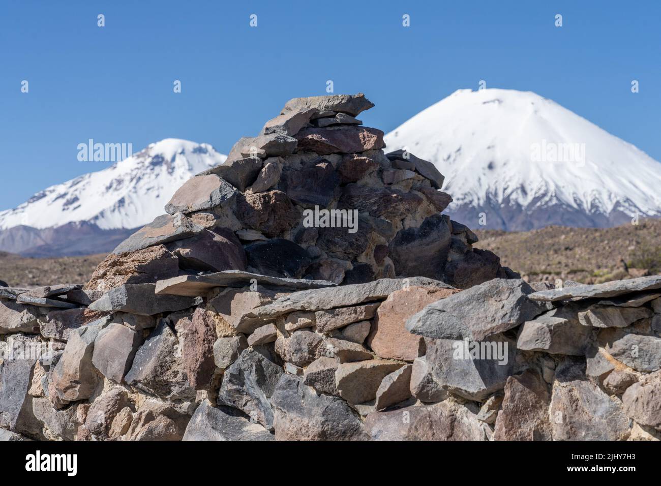 Mura in pietra rovinata di un villaggio vicino a Parinacota con Vulcani Parinacota & Pomerape nel Parco Nazionale Lauca, Cile. Foto Stock