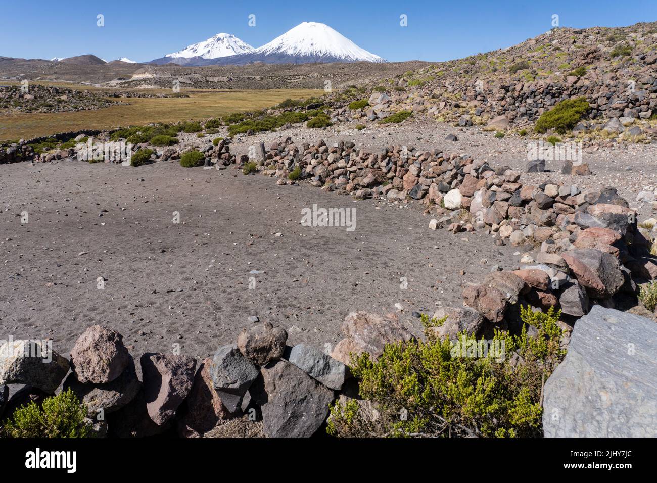 Pareti in pietra rovinata di una penna da lama vicino a Parinacota con Vulcani Parinacota & Pomerape nel Parco Nazionale Lauca, Cile. Foto Stock