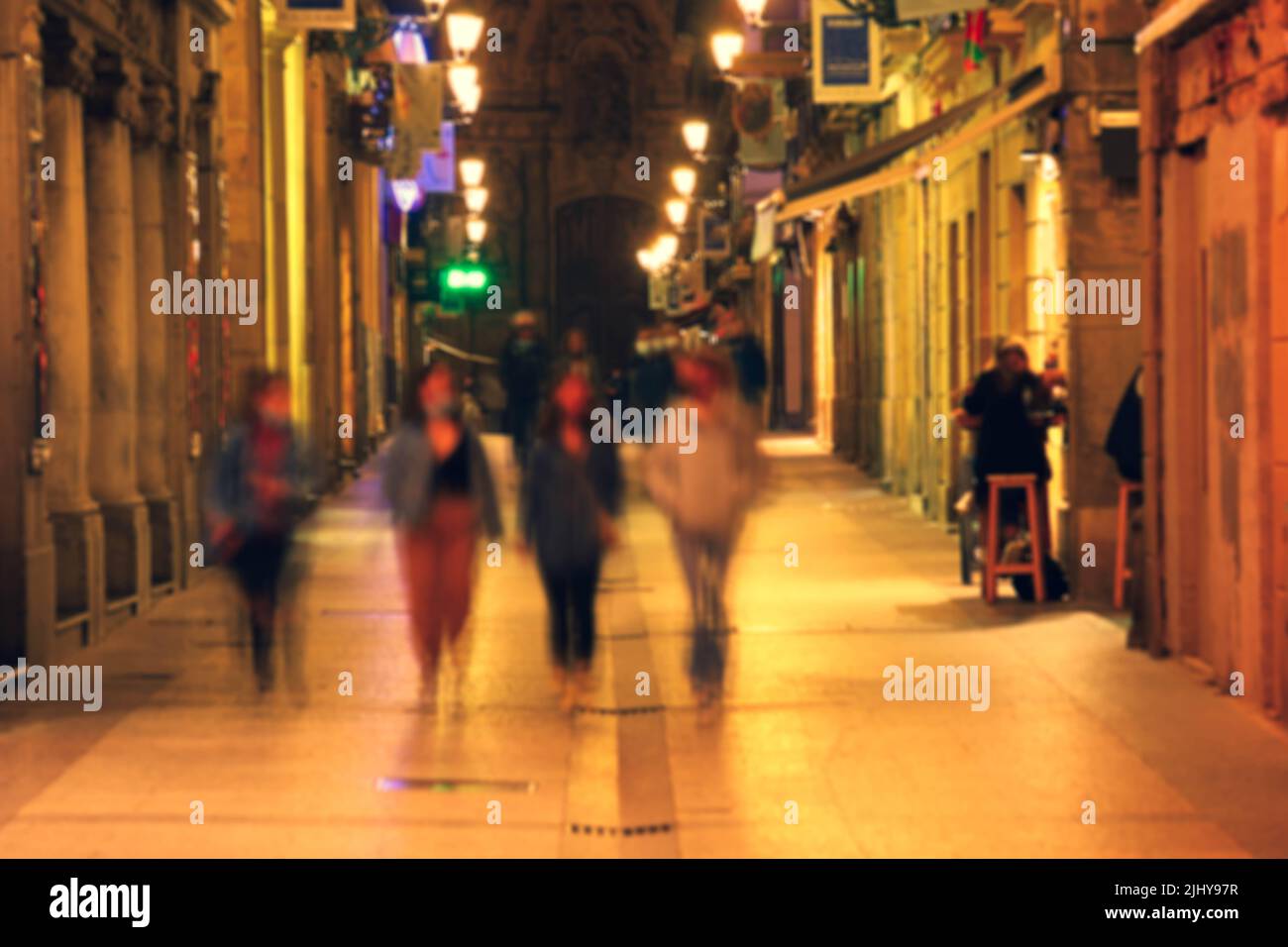 Immagine sfocata di San Sebastian tipica vista su una piccola strada con tapas bar animati e ristoranti di notte Foto Stock