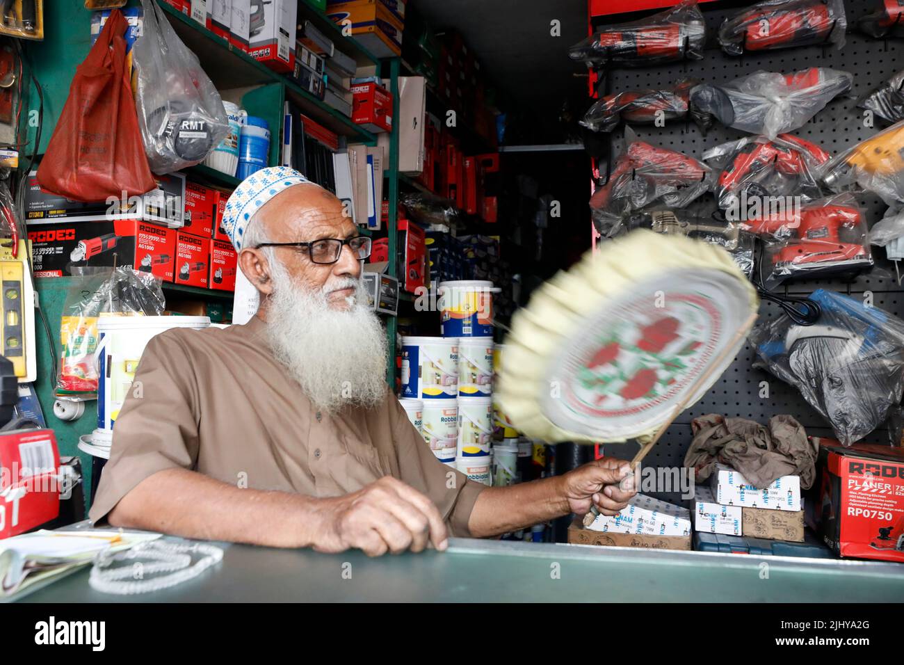 Dhaka, Bangladesh - 21 luglio 2022: Un negoziante in Shahjadpur di Dhaka usa un ventilatore a mano per ottenere sollievo dal calore durante lo spargimento di carico ha annunciato b Foto Stock