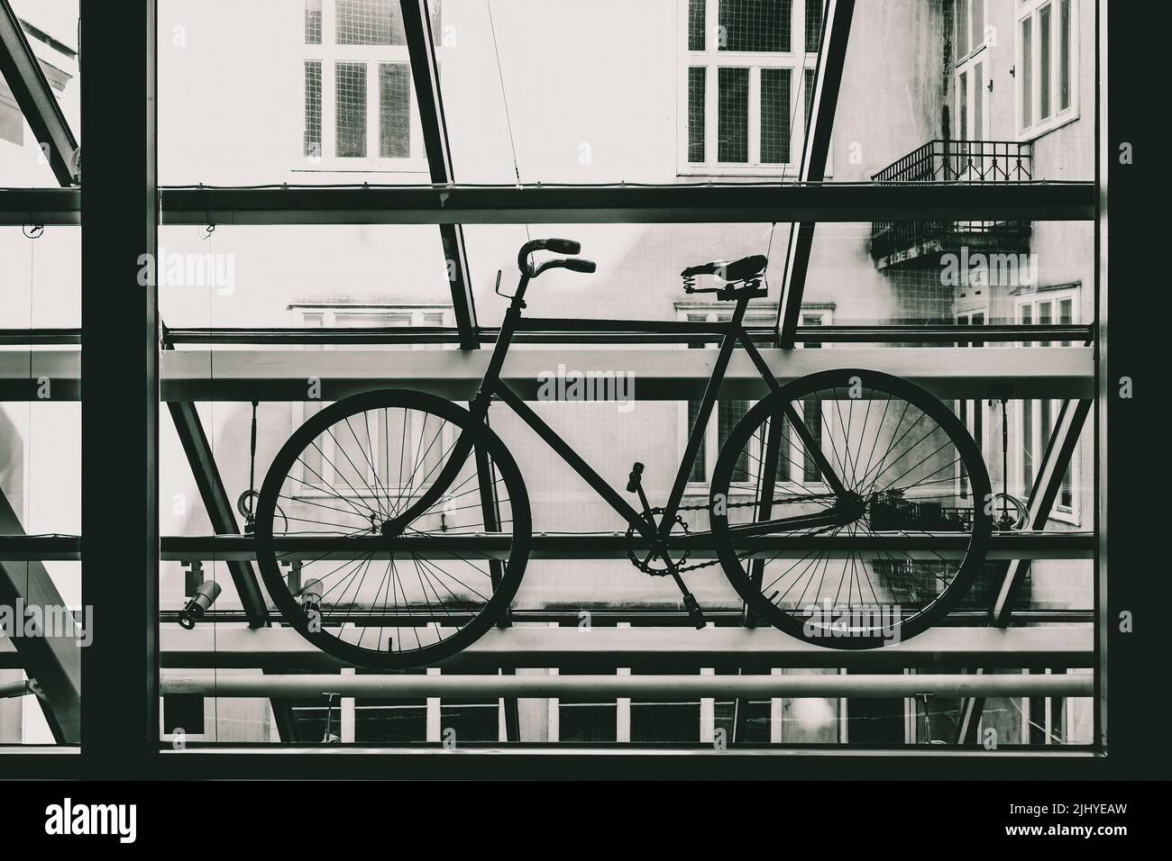Una foto in scala di grigi di una semplice bicicletta nel balcone Foto Stock