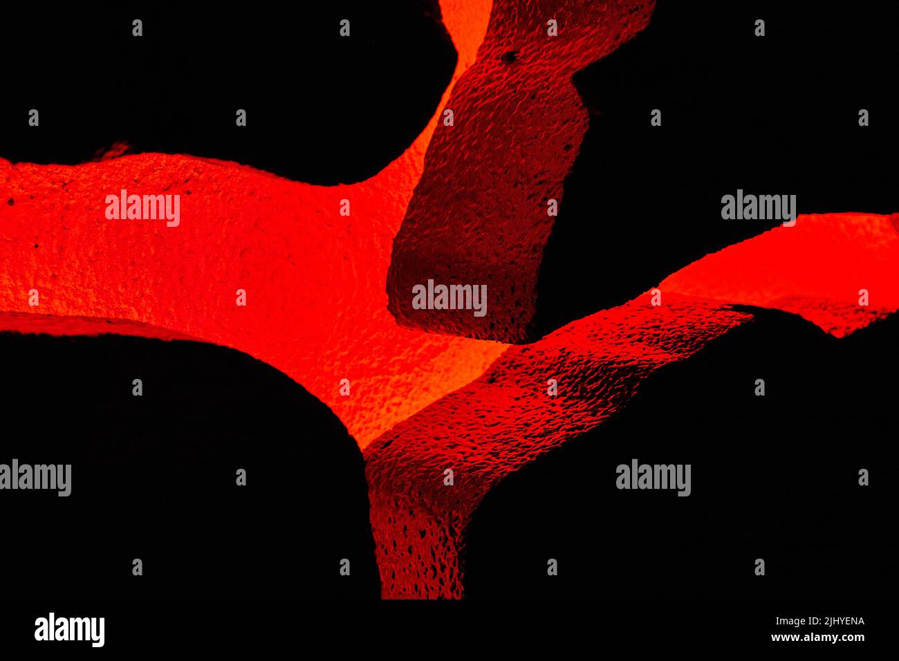 Vulcano rosso che risplenderà attraverso rocce testurizzate in mostra Foto Stock