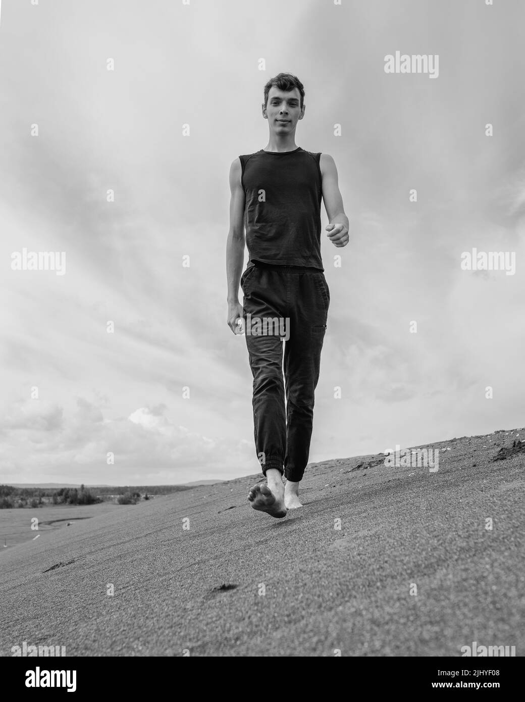 Giovane uomo che cammina da solo sulla sabbia nel deserto sabbioso Foto Stock