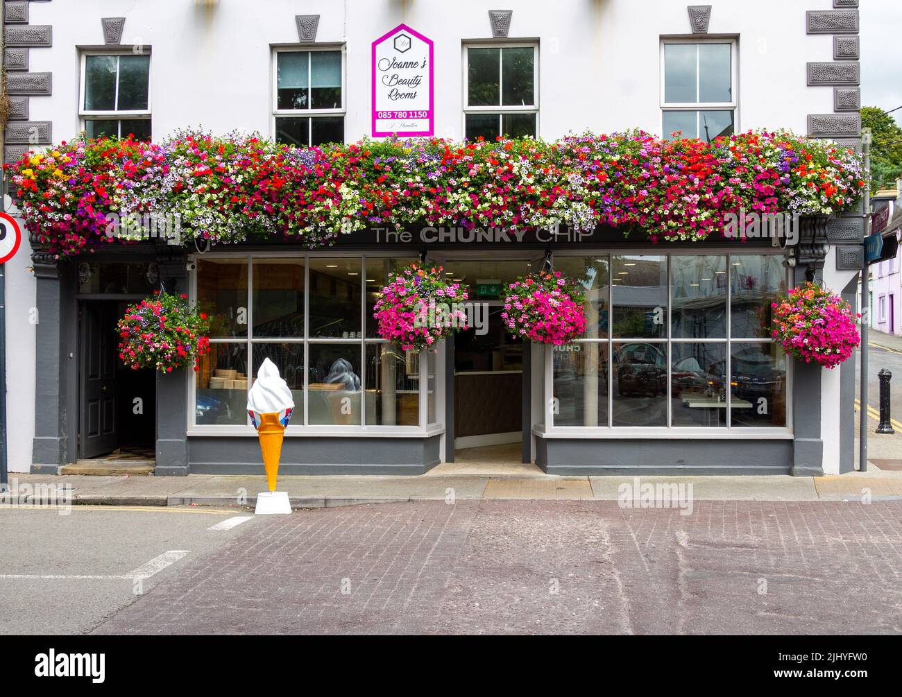 Mostra estiva di paniere appeso di Petunia sul fronte di un negozio. Foto Stock