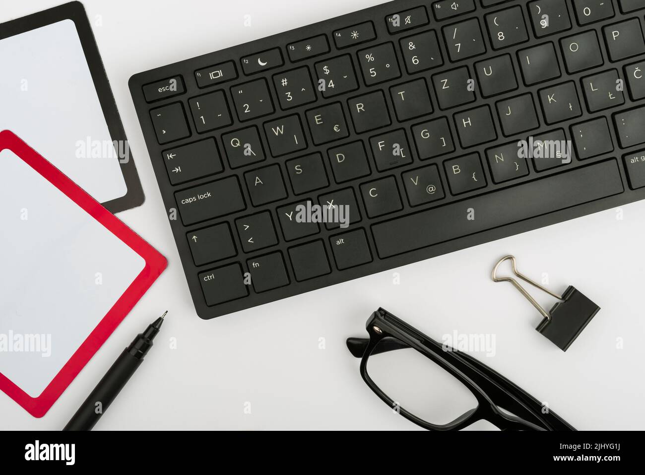 Una tastiera per computer, una penna e degli occhiali su un tavolo Foto Stock