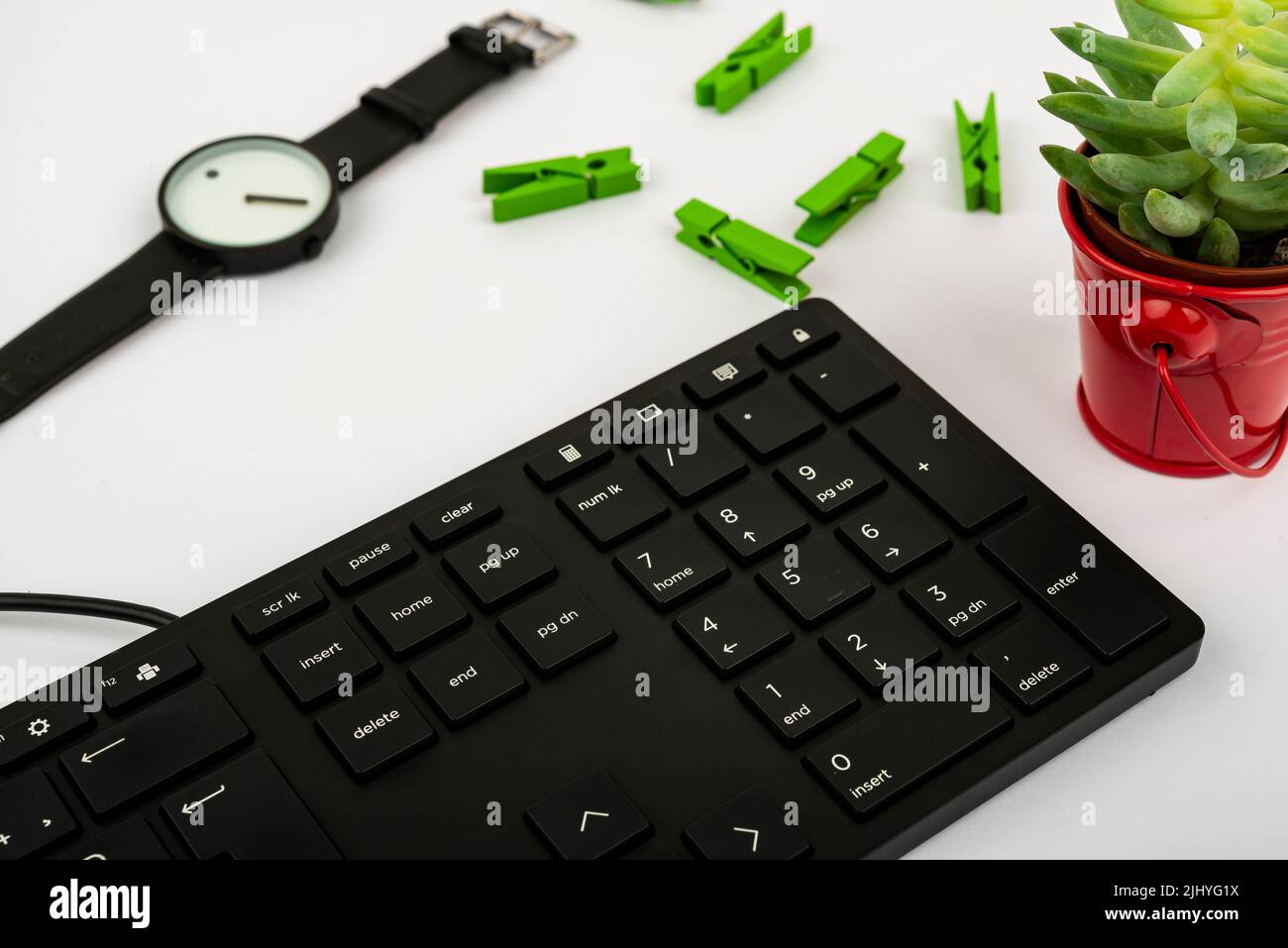 Una tastiera per computer, una pianta, un orologio e clothespins su un tavolo Foto Stock