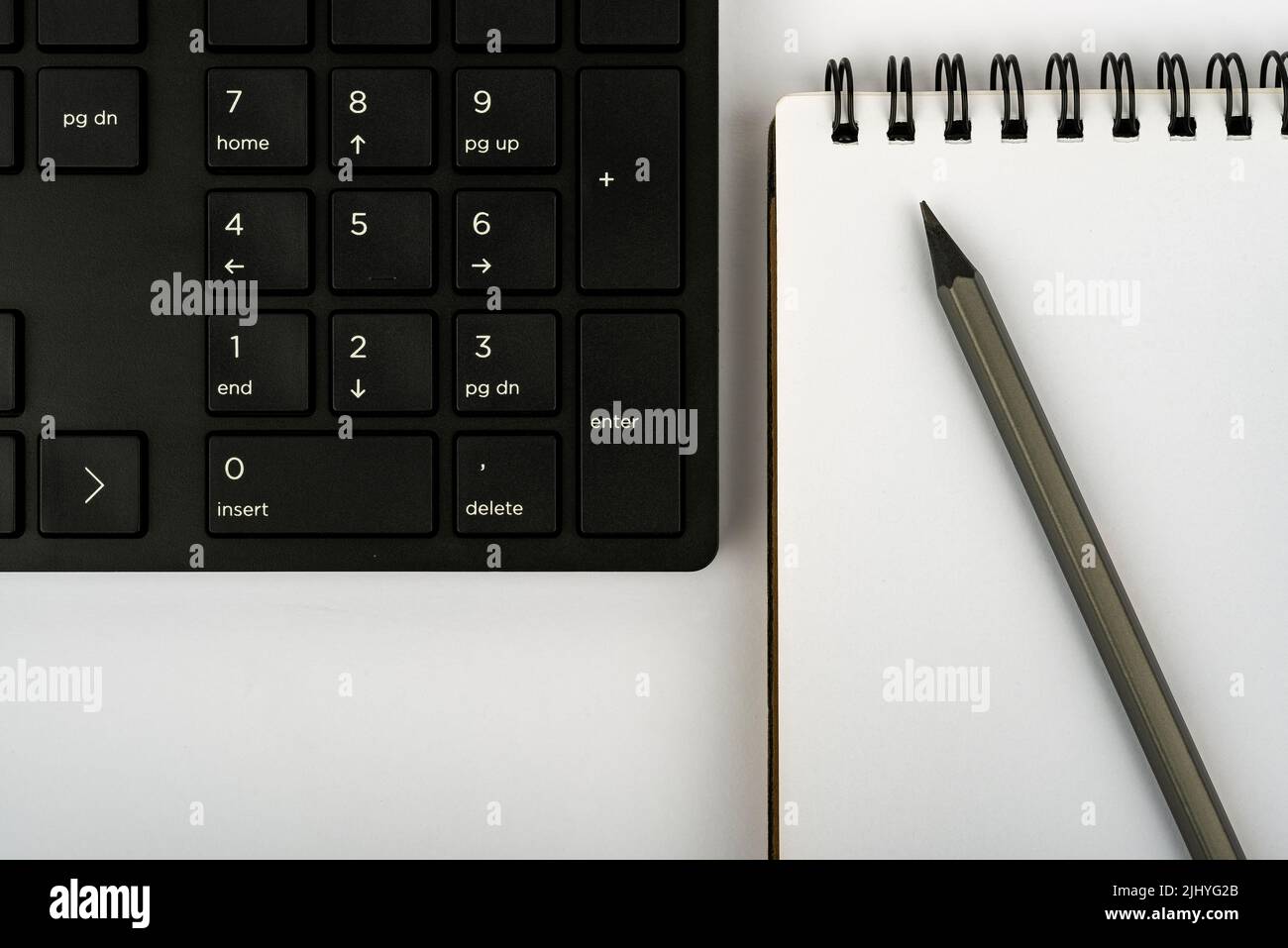 Una tastiera per computer, un notebook e una matita su un tavolo Foto Stock