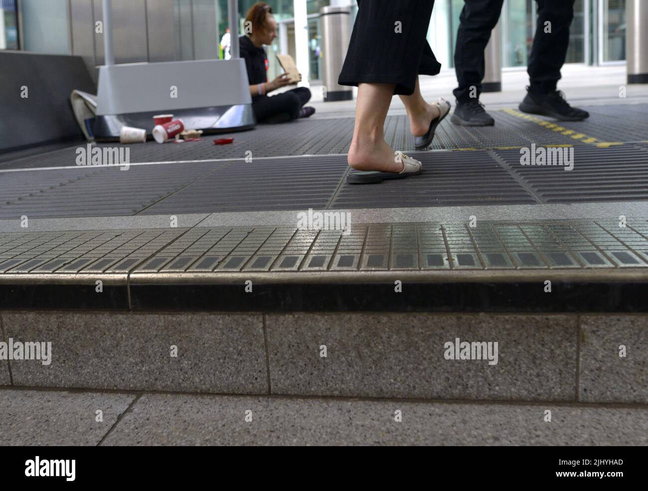 Londra, Inghilterra, Regno Unito. La gente che cammina davanti a una persona senza tetto che implora sui gradini della stazione della metropolitana Victoria Foto Stock
