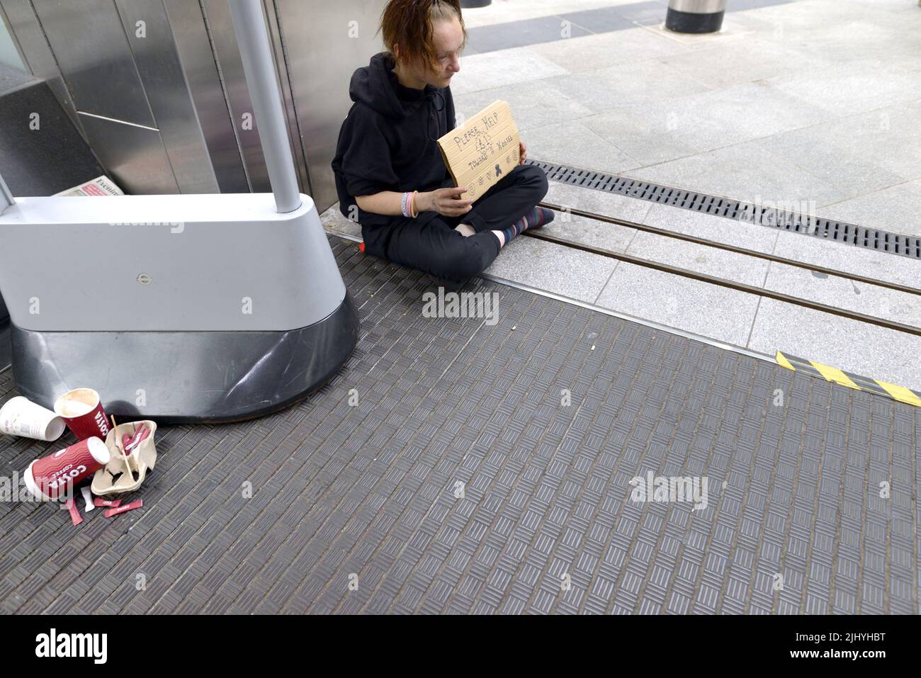 Londra, Inghilterra, Regno Unito. Giovane senzatetto che implora sui gradini della stazione della metropolitana Victoria Foto Stock