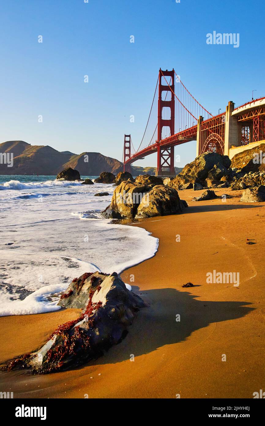 Ondeggia sulle splendide spiagge accanto al Golden Gate Bridge con luce dorata dal tramonto Foto Stock