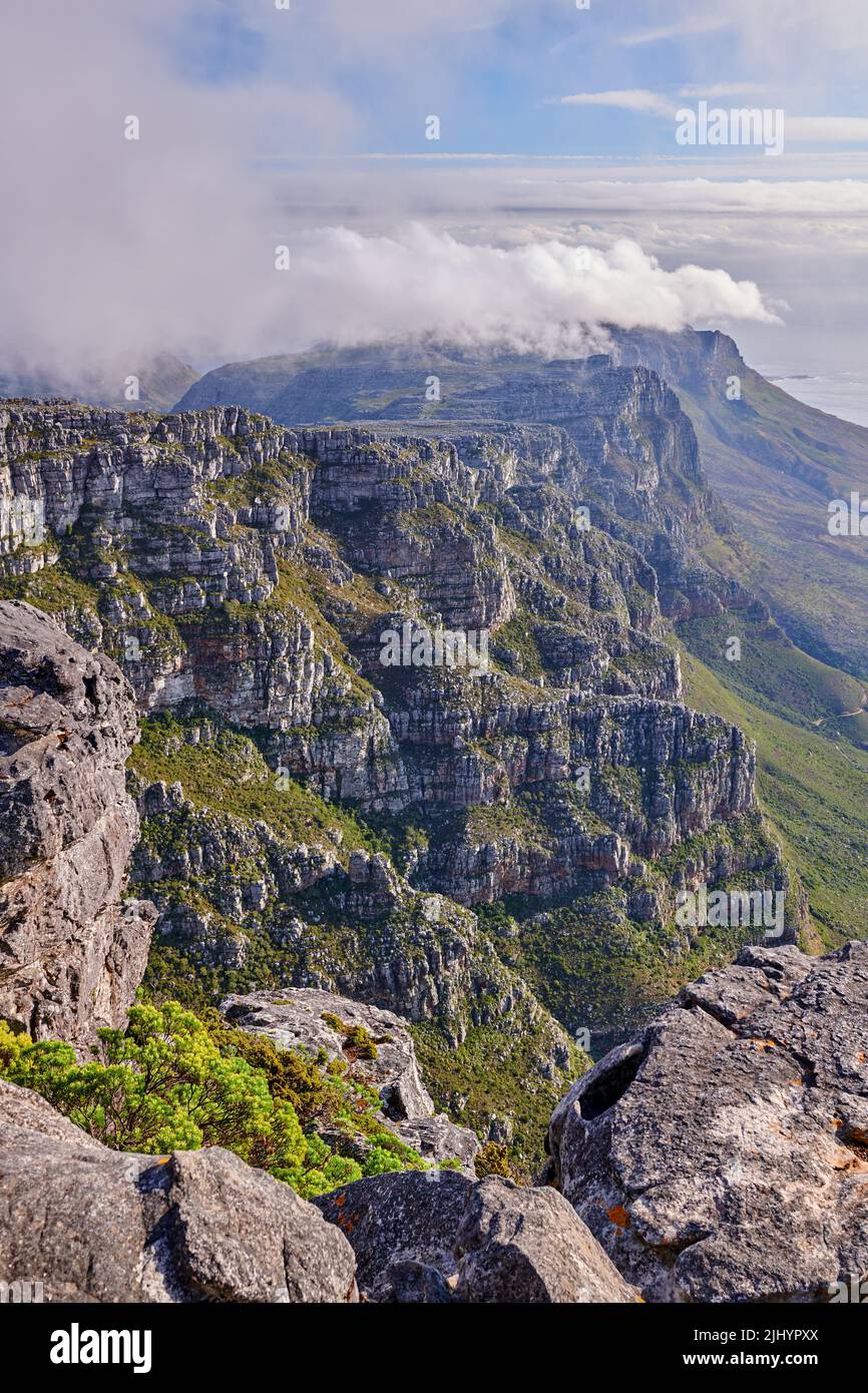 Bellissimo paesaggio di montagne rocciose con un cielo blu nuvoloso in una giornata estiva. Vista panoramica e tranquilla di un picco con grandi rocce e erba. Un vertice Foto Stock