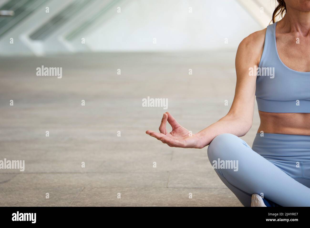 donna che medita in una posa yoga, sfondo urbano concreto Foto Stock