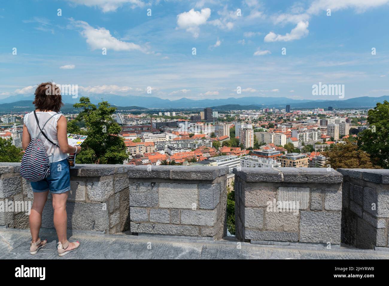 Turista femminile con mappa della città che domina la città di Lubiana dalle antiche merlature del castello. Lubiana, Slovenia Foto Stock