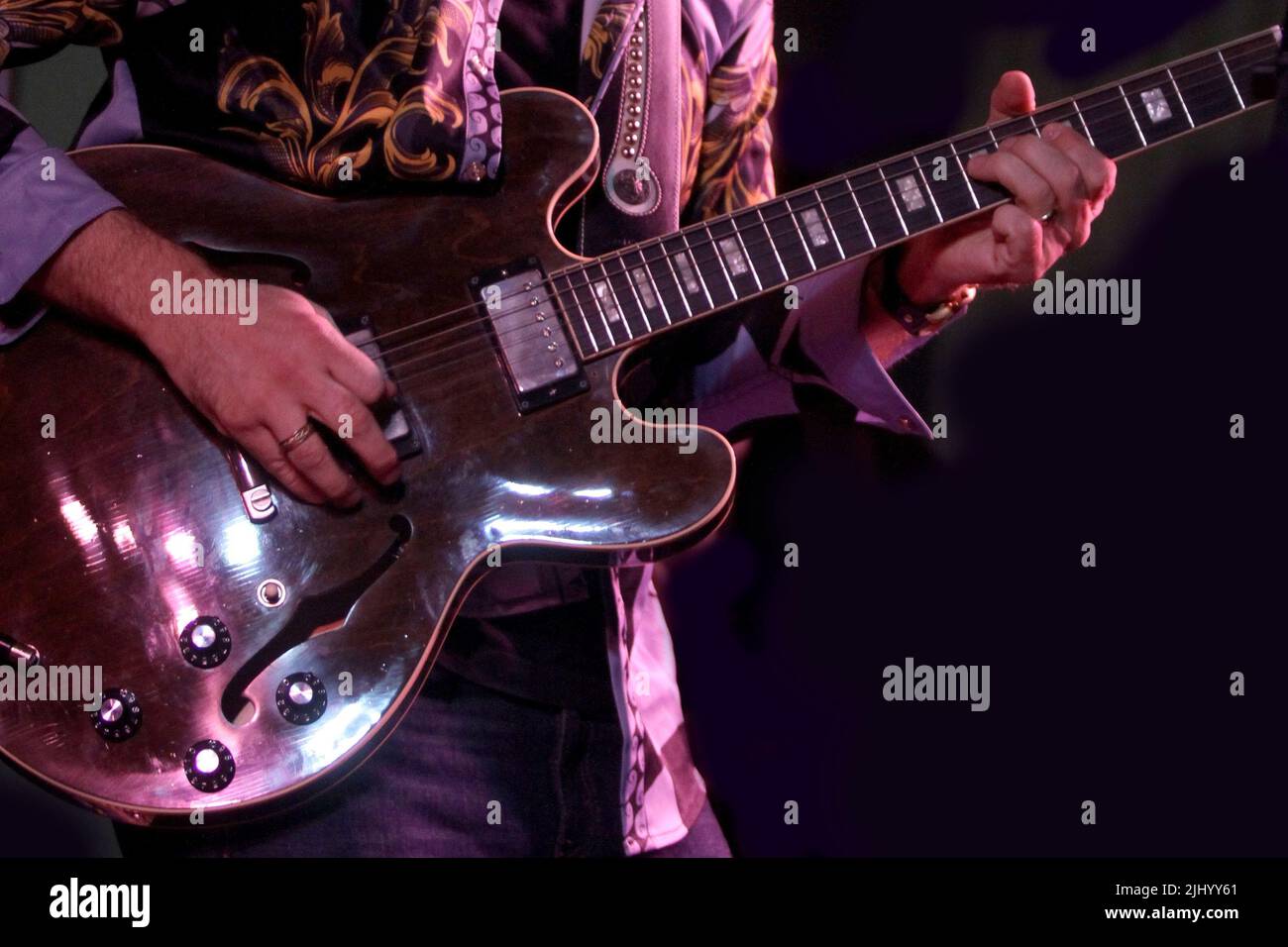Un musicista suona su chitarra elettrica sotto le luci del palco. Foto Stock