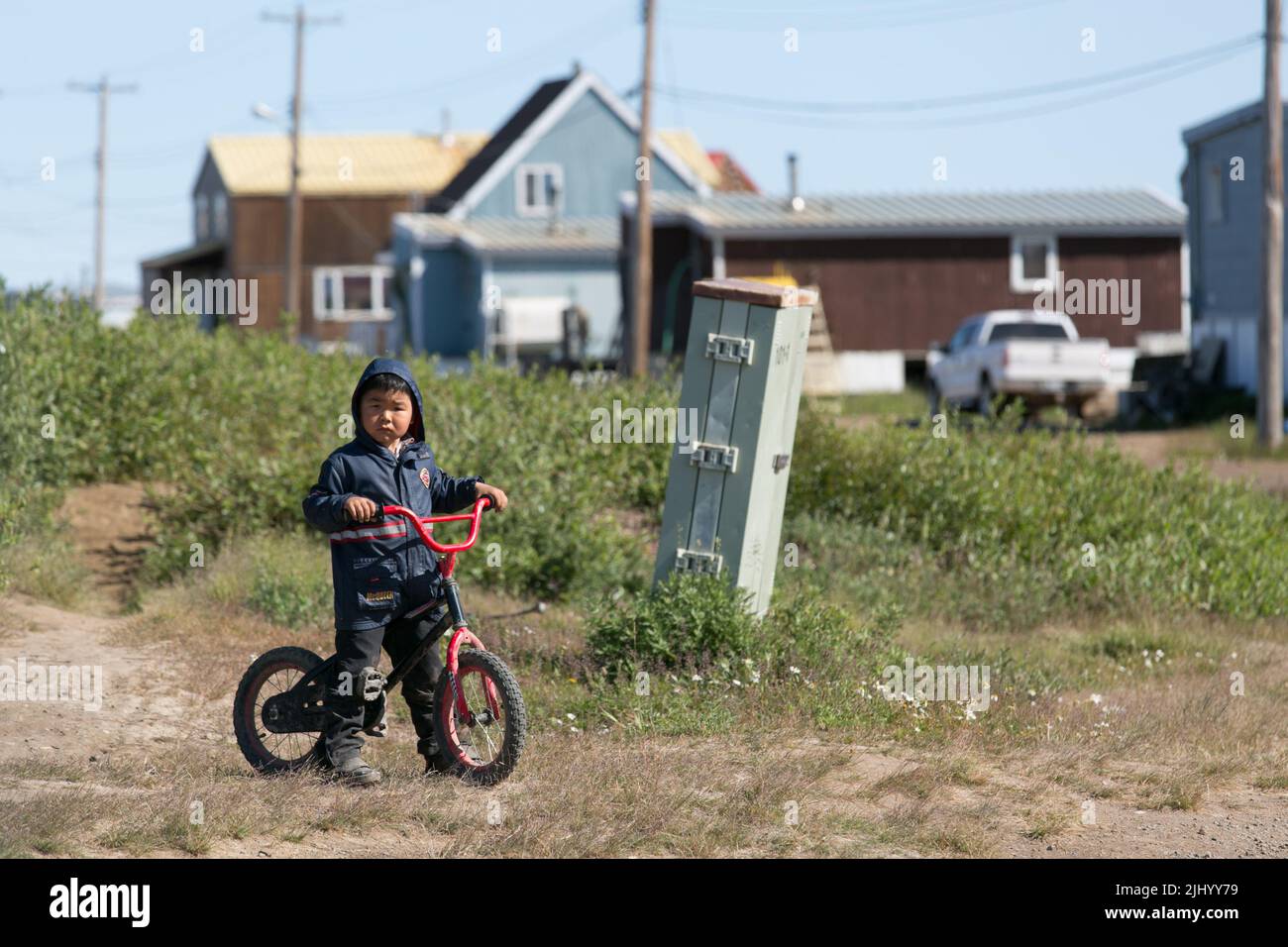 Giovane ragazzo in bicicletta in estate nella comunità Inuvialuit di Tuktoyaktuk, Artico occidentale, territori nordoccidentali, Canada. Foto Stock
