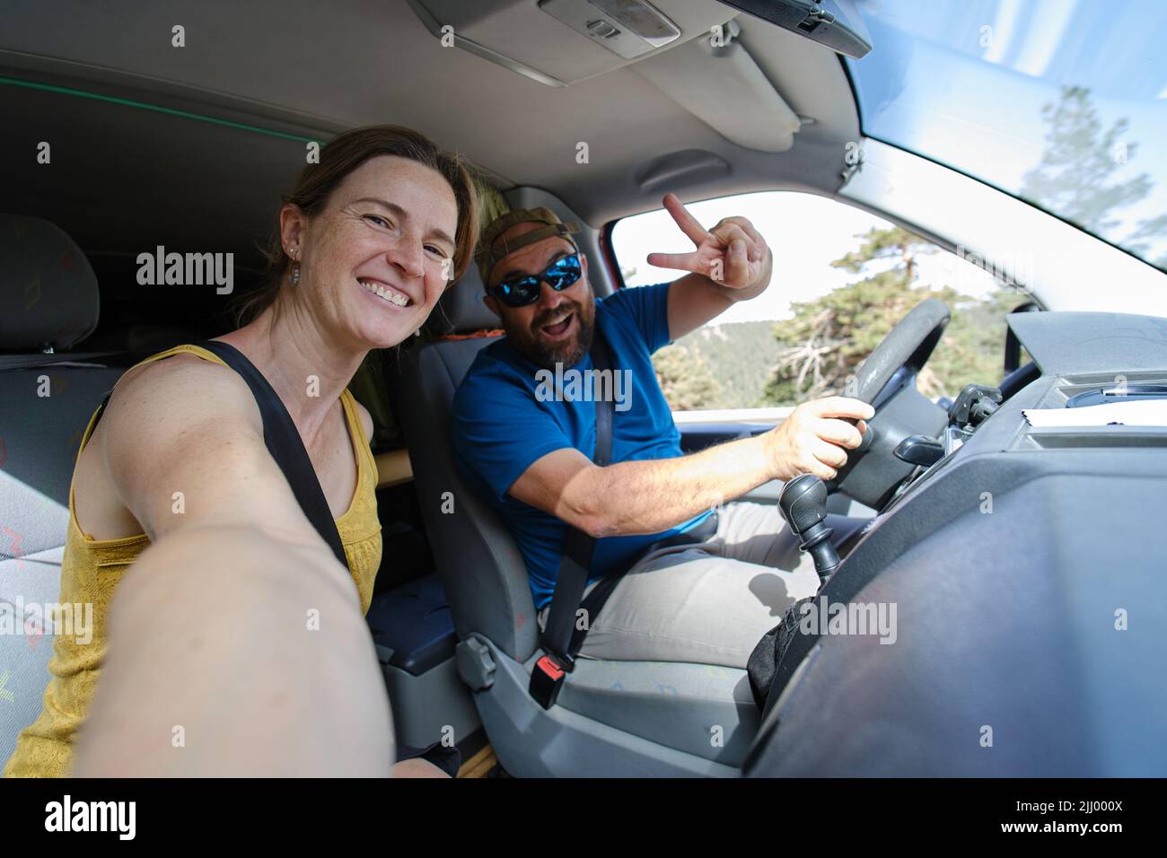 Una coppia positiva che prende selfie in auto Foto Stock