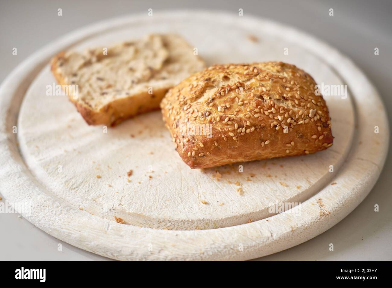 Pane integrale seminato affettato. Fette fresche marroni fatte in casa o rotolare su un tagliere di legno servito come un pranzo sano, pasto a base di snack per la colazione Foto Stock