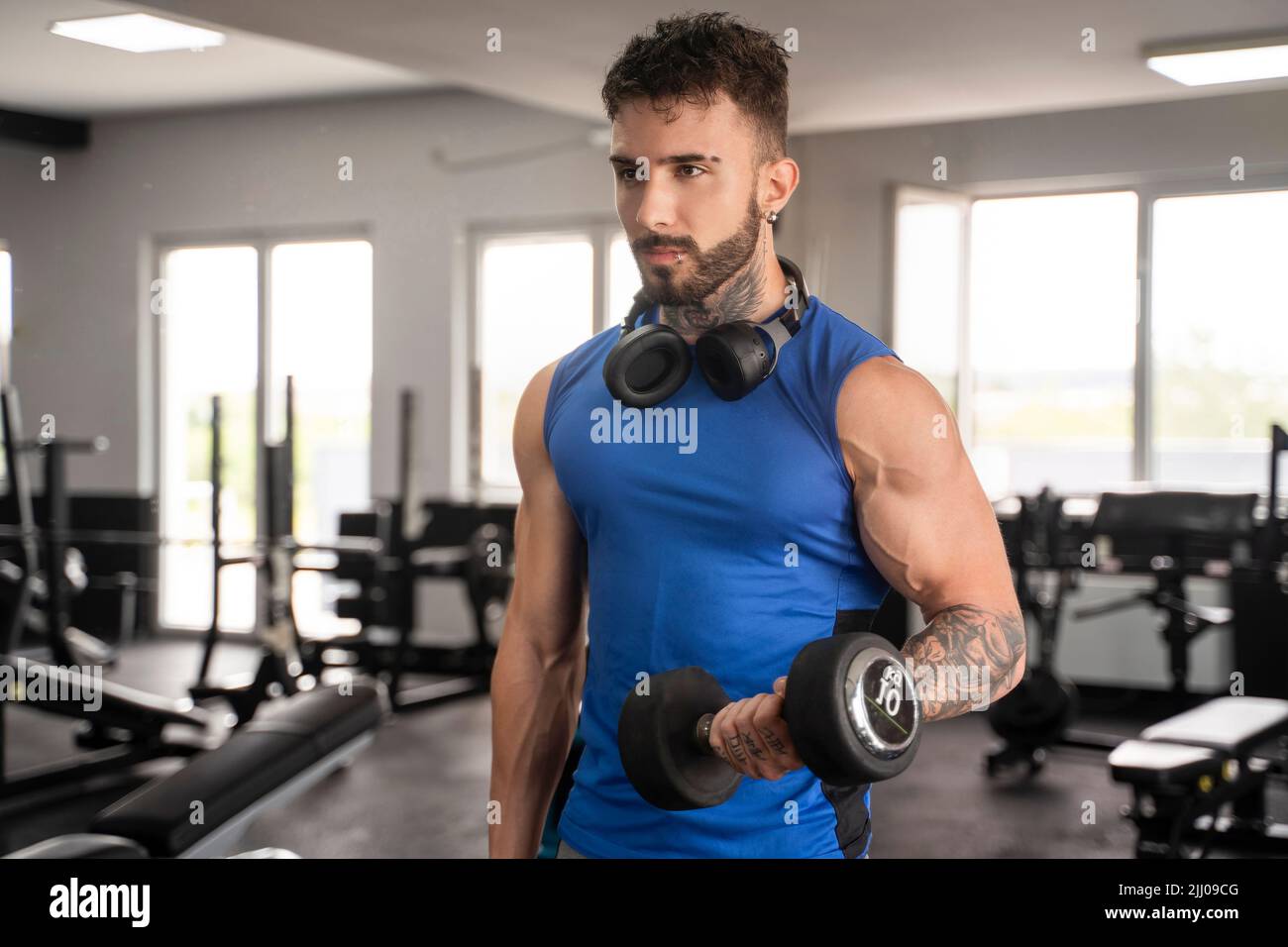 Bel maschio con tatuaggi nel suo allenamento 20s in palestra Foto Stock