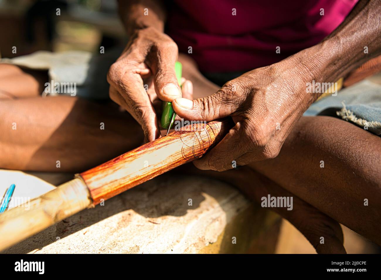 Mano di una persona indigena che intagliano sulla superficie del cannello o del sumpit. Foto Stock