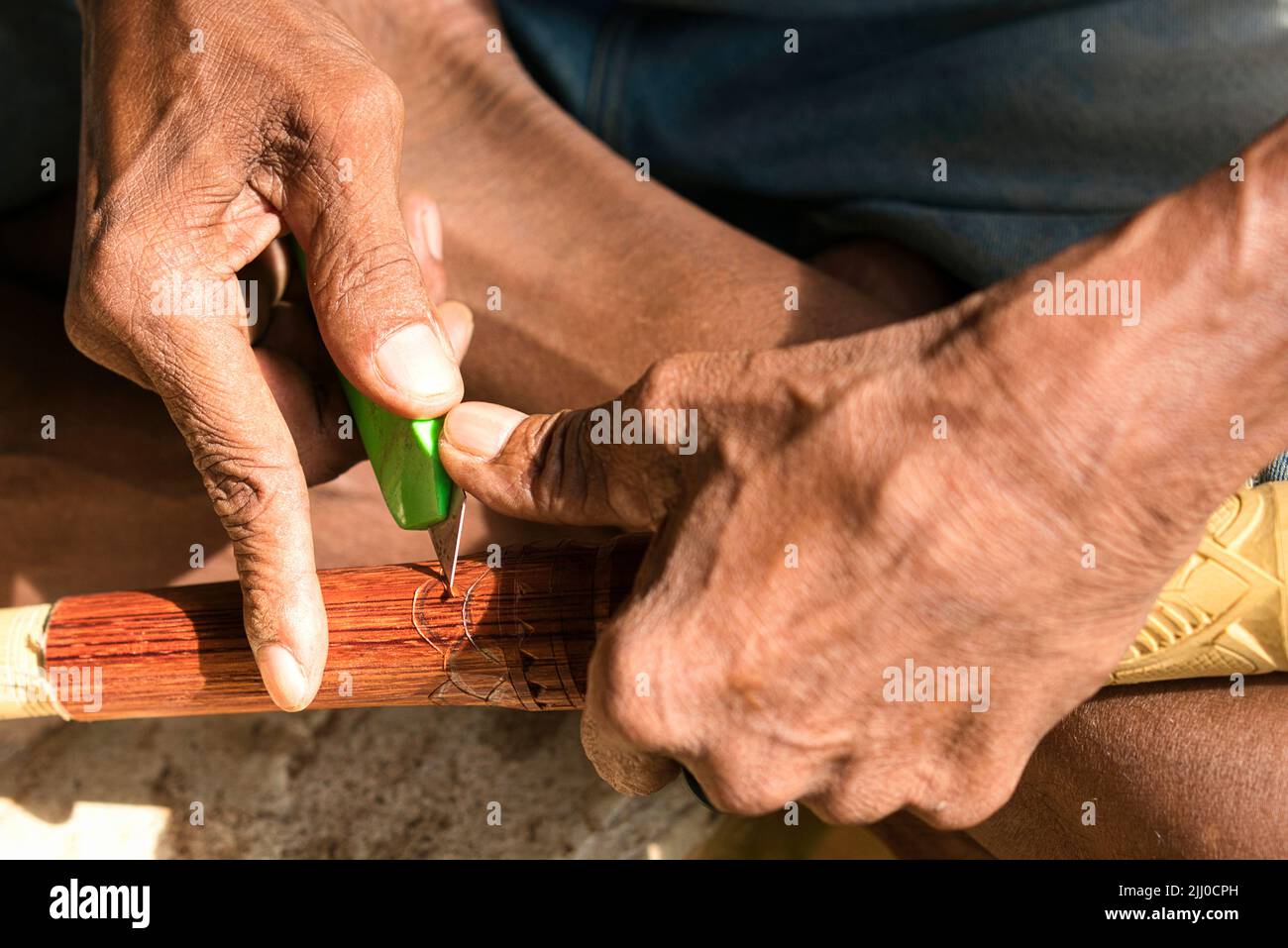 Mano di una persona indigena che intagliano sulla superficie del cannello o del sumpit. Foto Stock