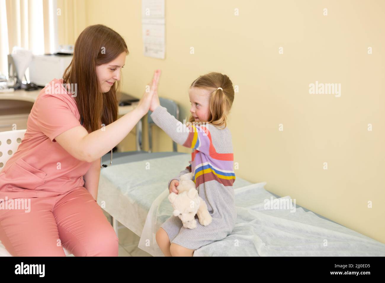 paziente di 4 anni con gioiosa alta fives per il medico femminile Foto Stock