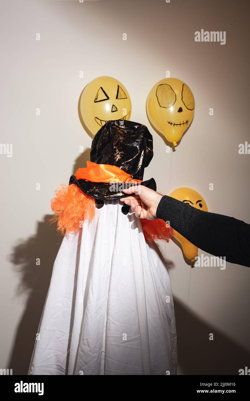 I bambini si vestono per celebrare Halloween felice. Fantasma bianco in costume fatto in casa da foglio e dipinto con palline arancioni sulla parete. Design festivo, concetto di festa. Festa di tutti i Santi. Foto Stock