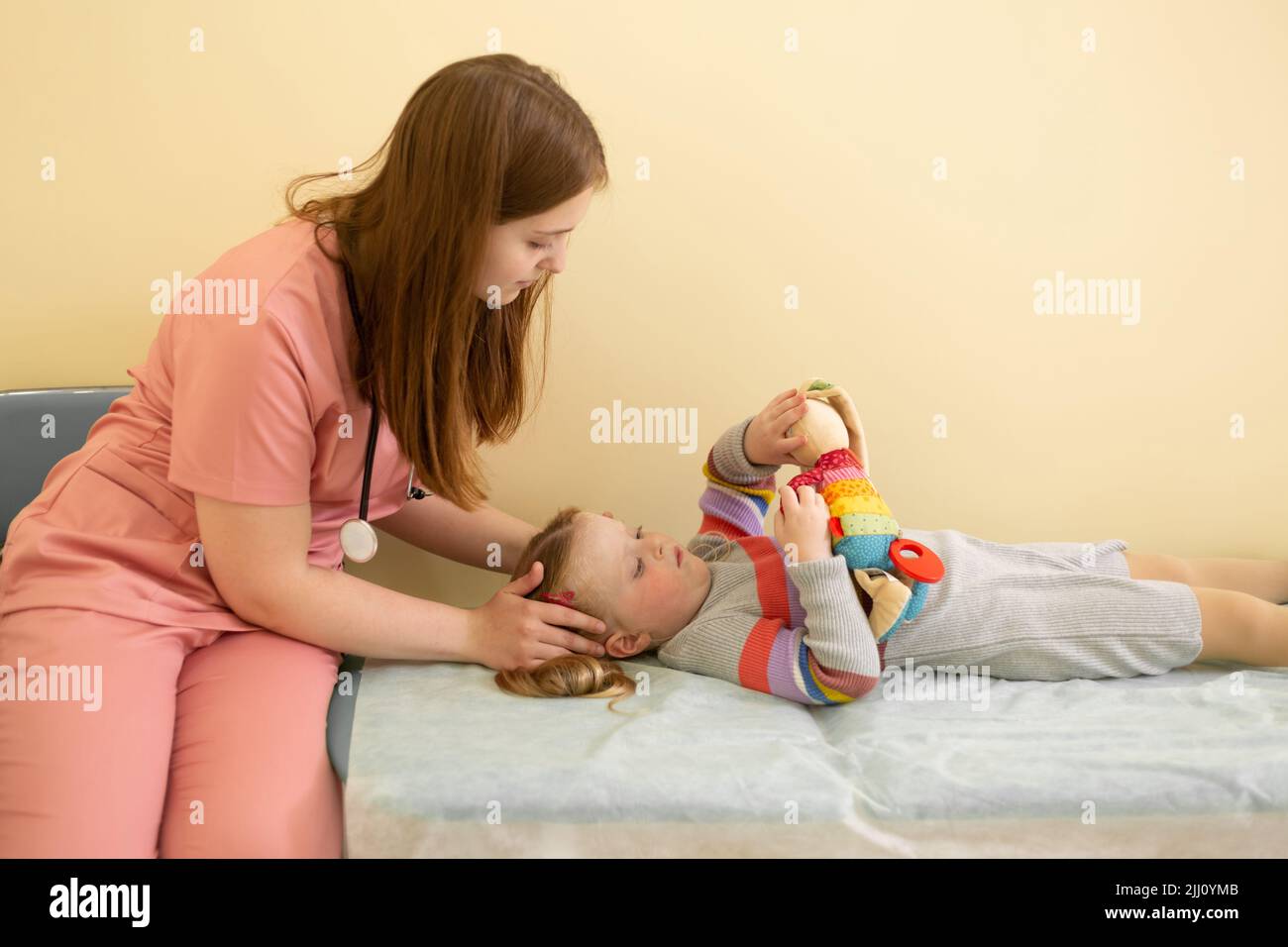 Donna pediatra che dà il massaggio della testa alla bambina in ospedale Foto Stock