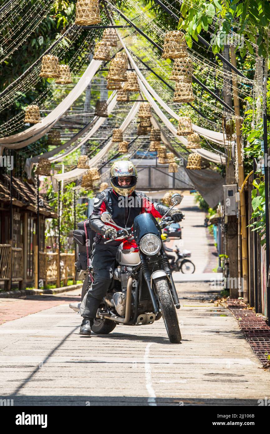 Uomo anziano che guida la sua moto classica nel nord della Thailandia Foto Stock