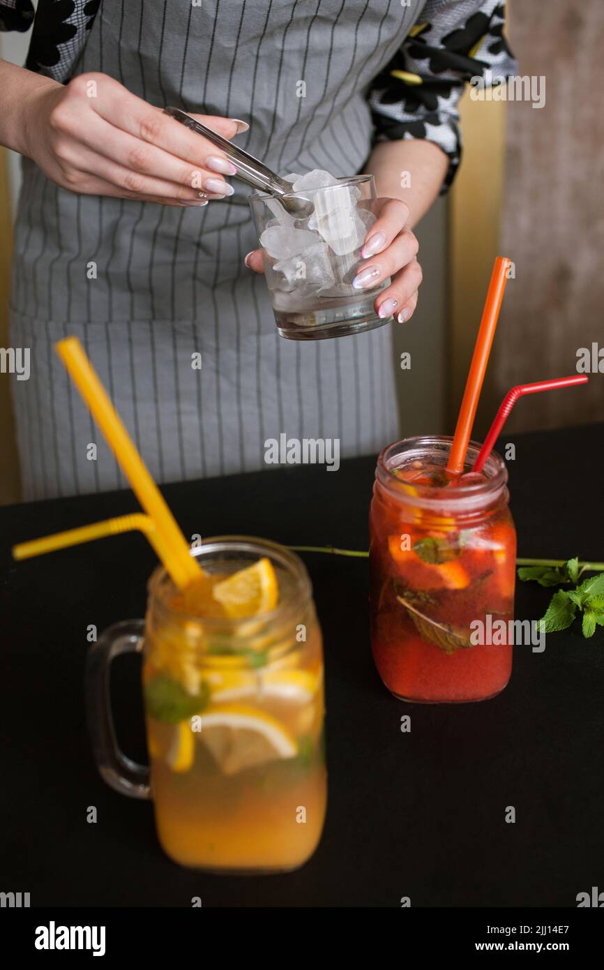 Il cameriere mette un pezzo di ghiaccio in un bicchiere di cocktail Foto Stock