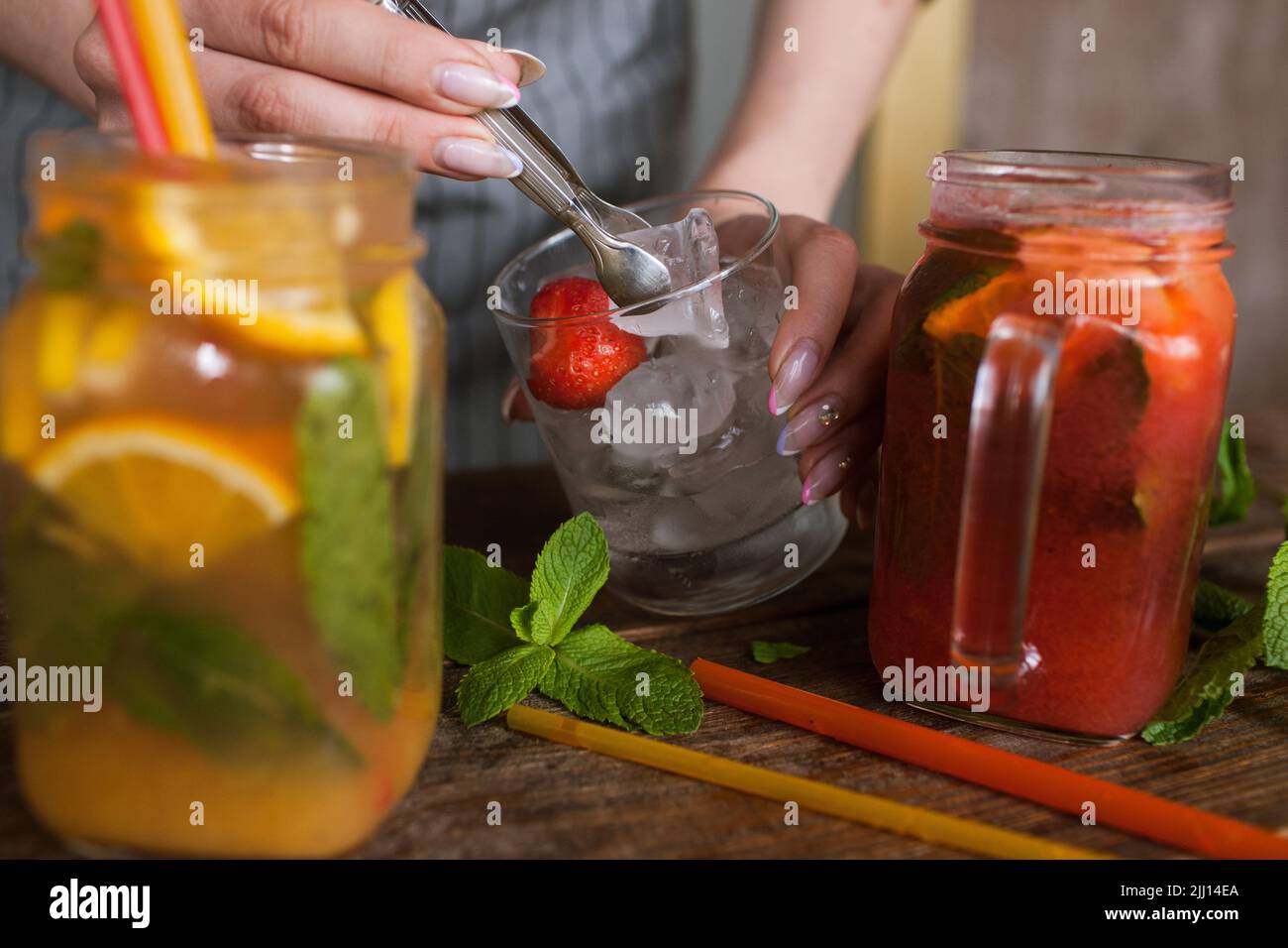 Il cameriere mette un pezzo di ghiaccio in cocktail di frutta Foto Stock