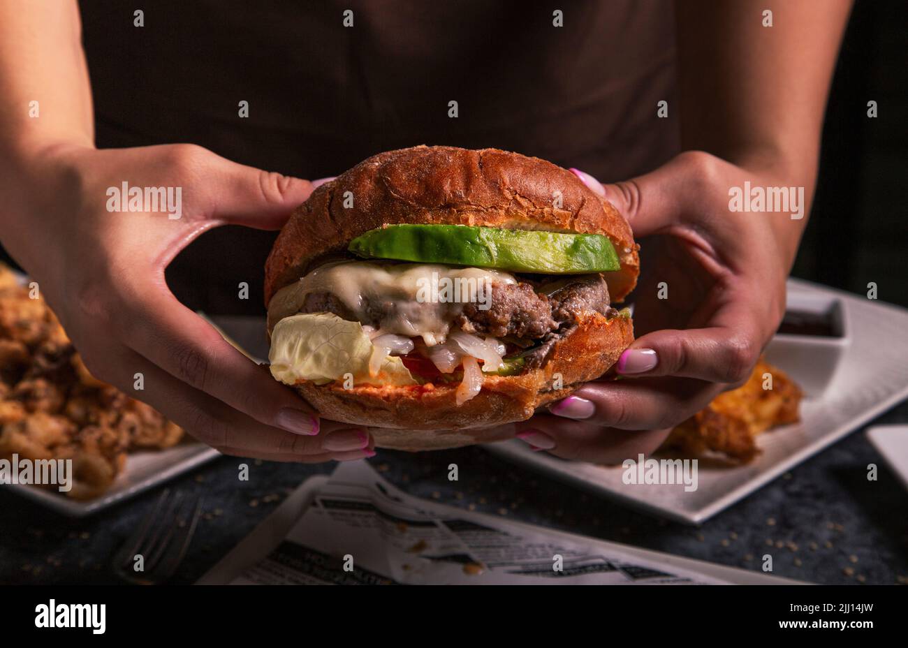 fast food, persone e cibo malsano concetto - primo piano di donne mani con hamburger. Foto Stock
