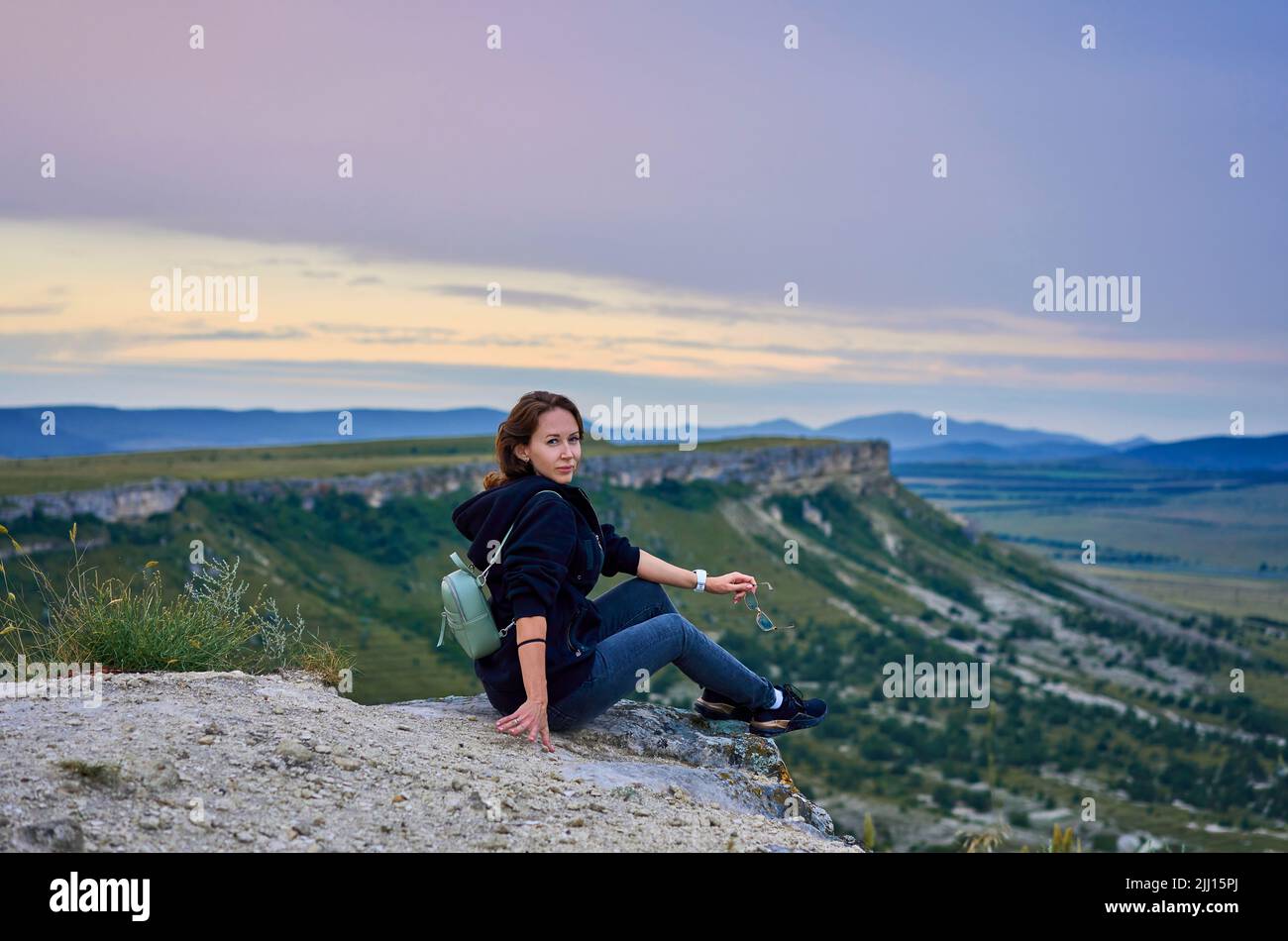 ragazza è seduta sulla cima di una montagna Foto Stock