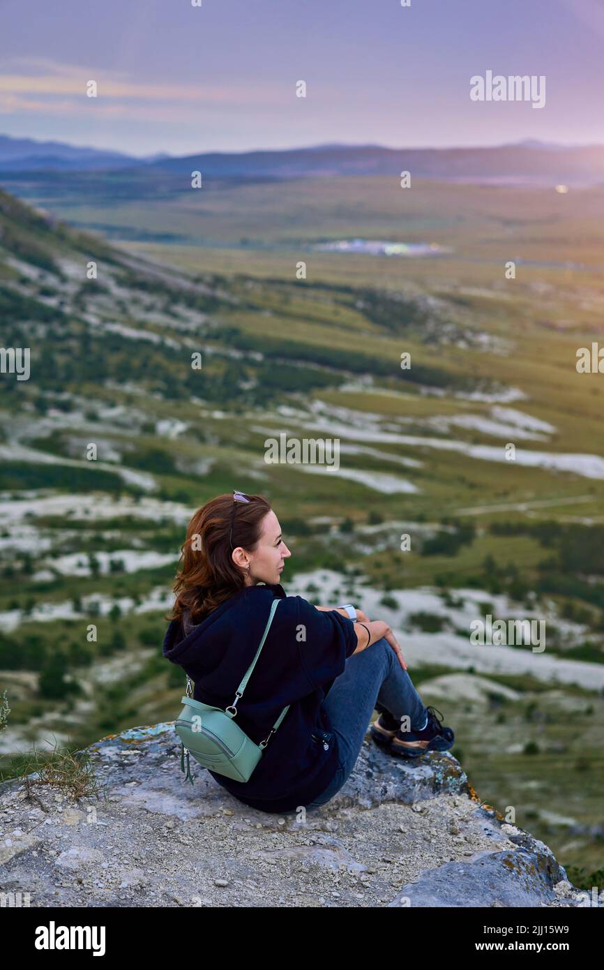 ragazza è seduta sulla cima di una montagna Foto Stock