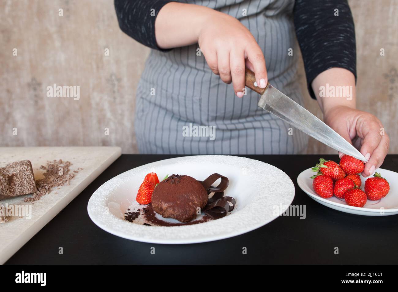 La donna cuoca decora un delizioso dessert al cioccolato Foto Stock
