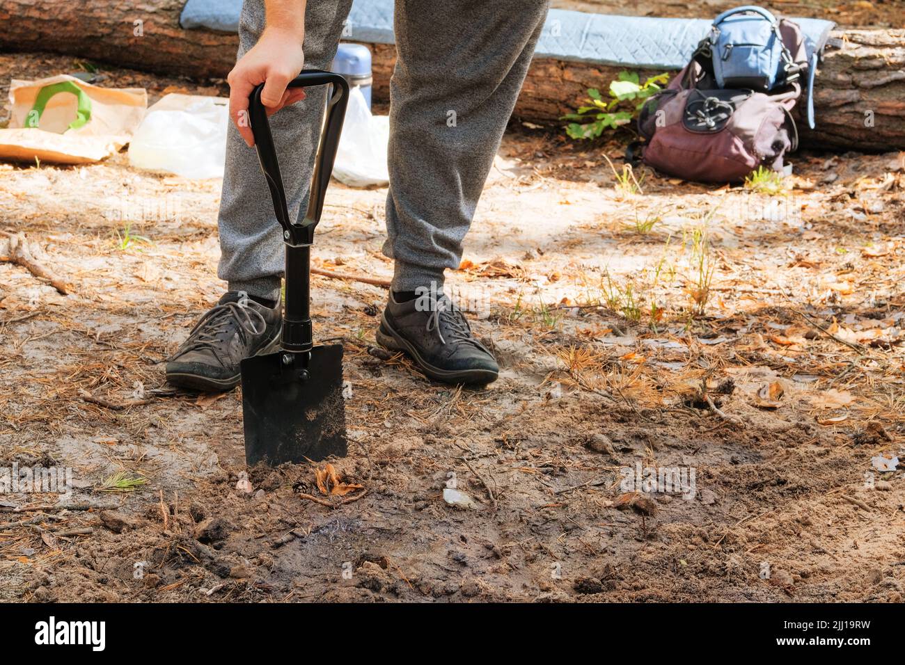 Il viaggiatore scava terreno con una pala nella foresta. Pala nera in mani umane. Foto Stock
