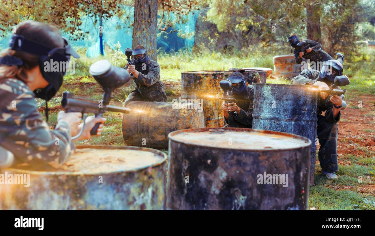 Gruppo di giocatori di paintball di squadre opposte in sparo in avanti Foto Stock