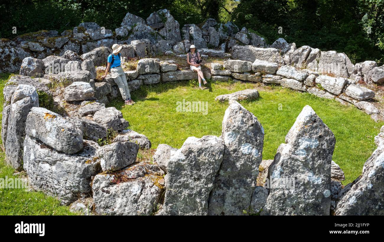 Visitatori del 21st ° secolo che riposano sulle fondamenta dell'età del ferro di un rifugio-cerchio a DIN Lligwy, Moelfre, Anglesey, Galles, Regno Unito Foto Stock
