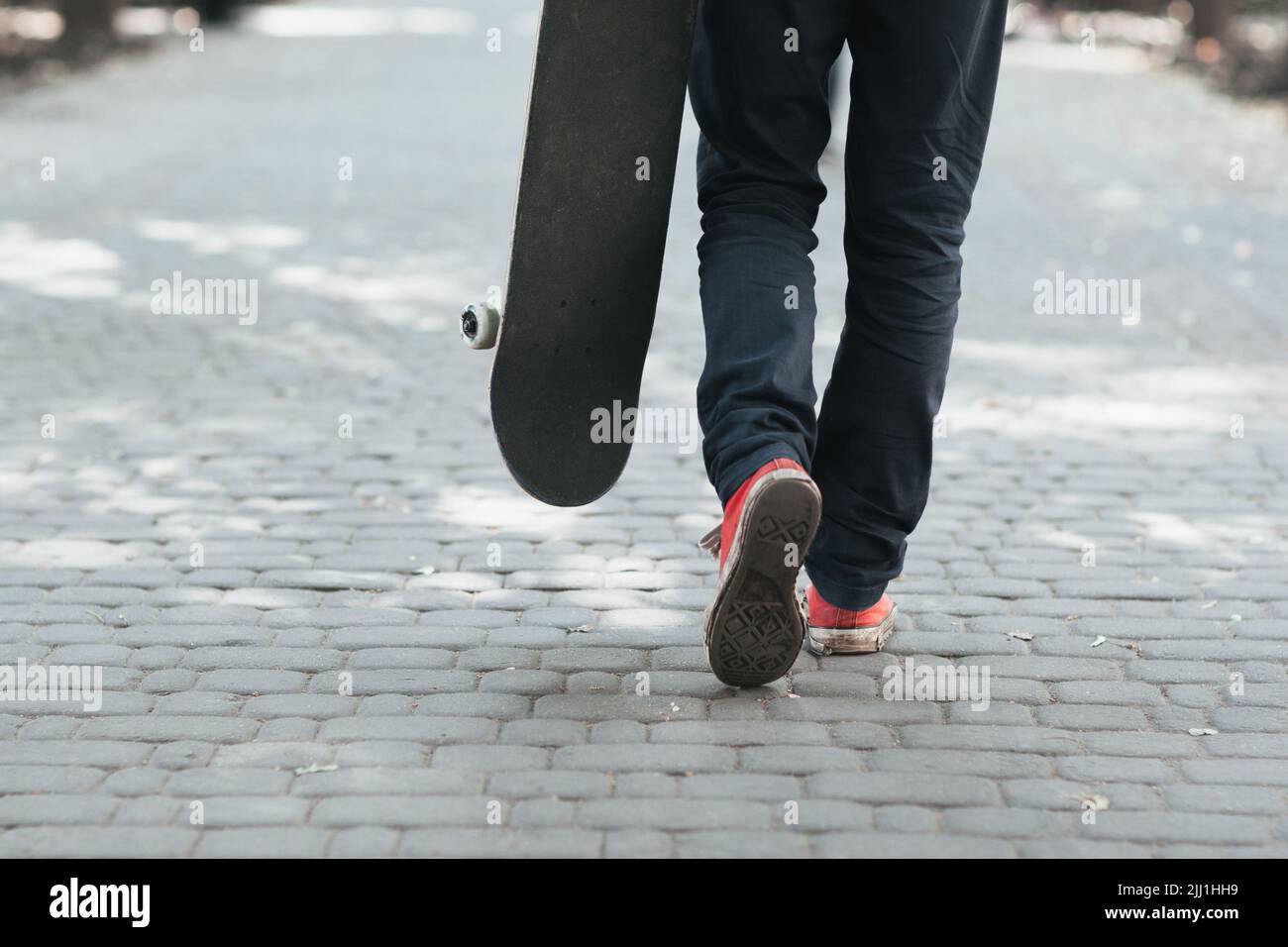 Skateboarder a piedi in strada. Concetto di vita cittadina Foto Stock