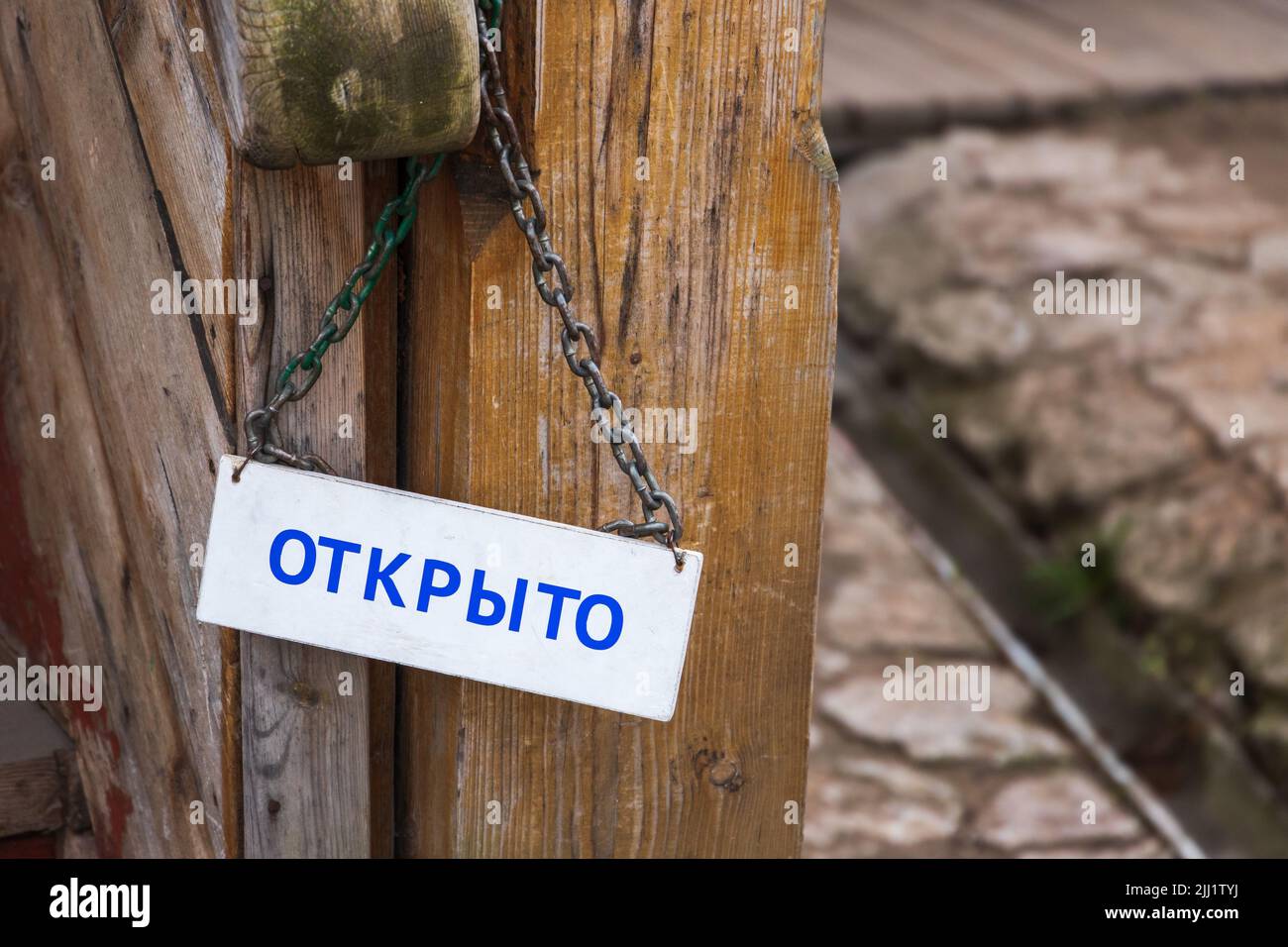 Lavagna bianca con testo aperto in russo appeso alla porta in legno d'epoca Foto Stock