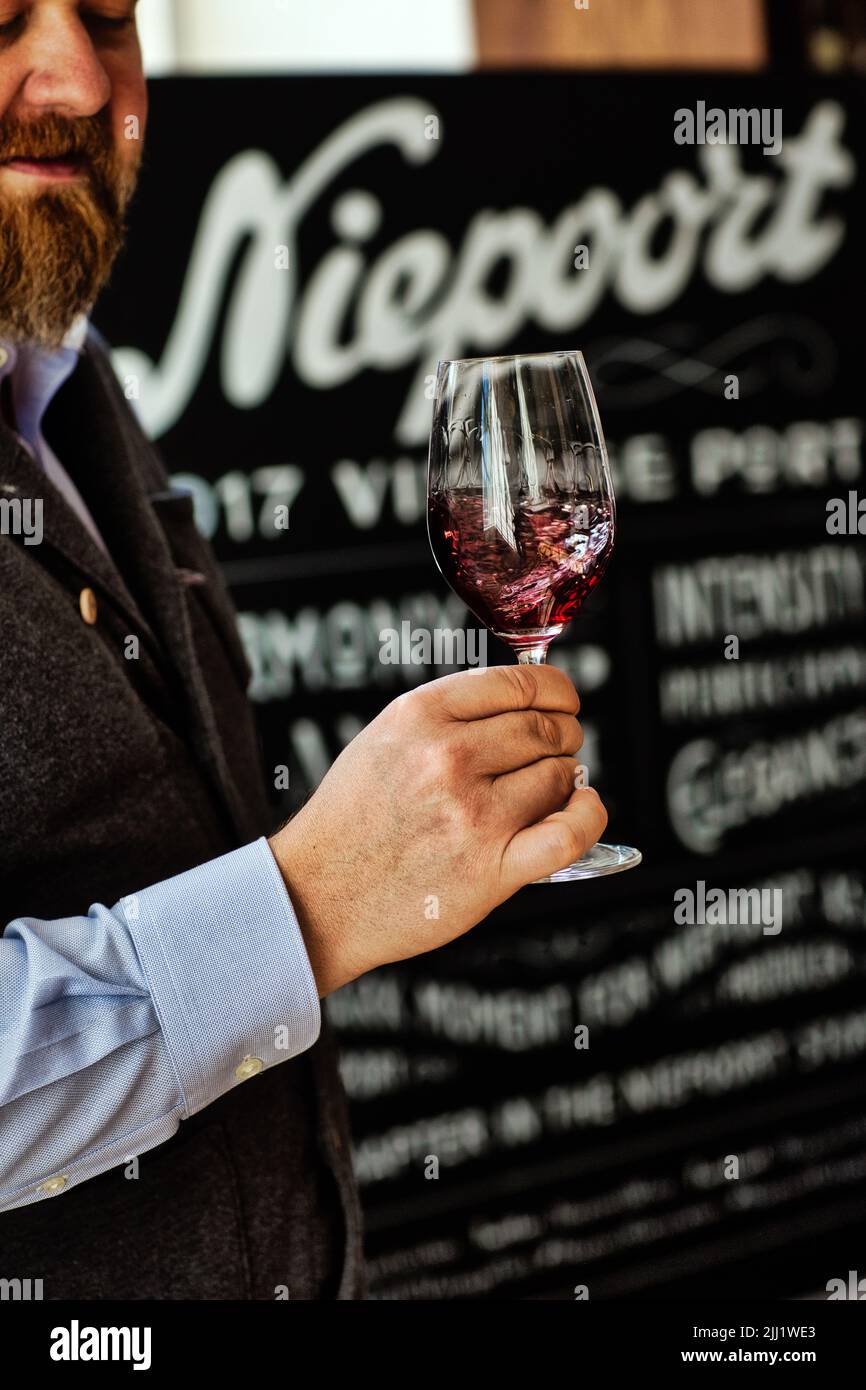 Vino di porto di degustazione maschile in bicchiere. Una persona tiene un bicchiere di vino prima della degustazione. Foto Stock